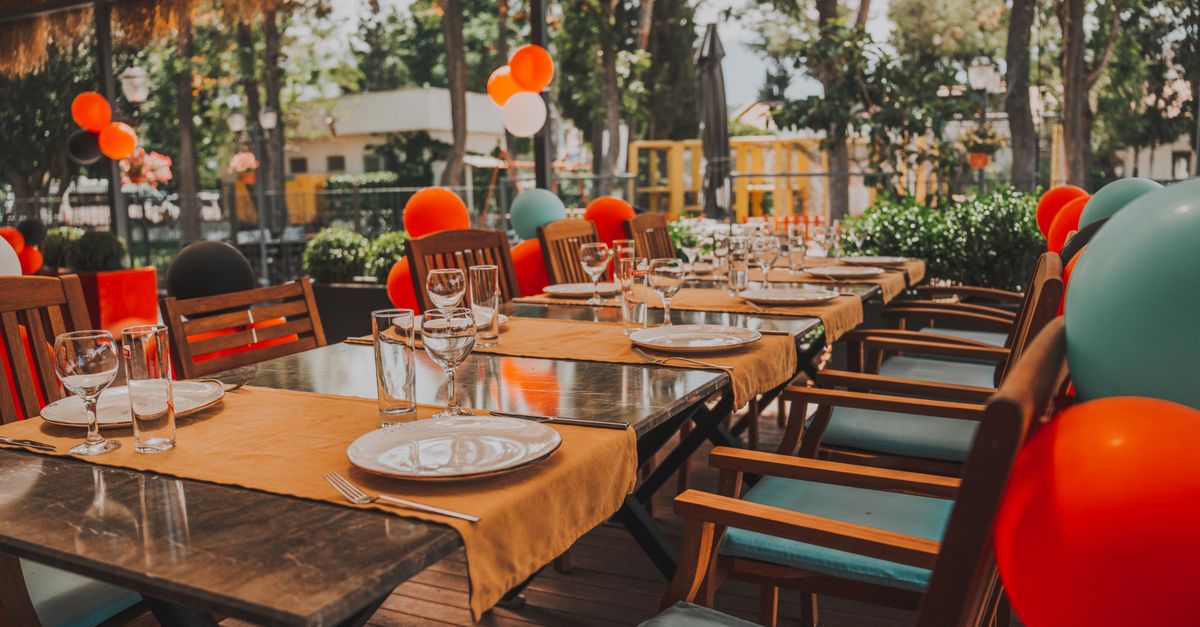 Outdoor table set for a celebration, adorned with colorful balloons creating a festive mood.